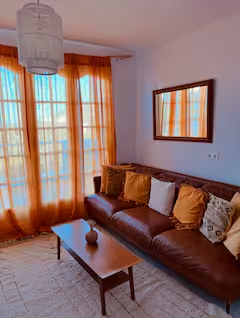 Sitting room with leather sofa and terracotta curtains