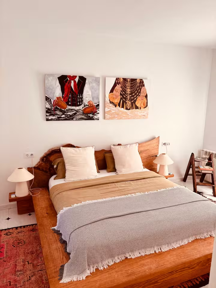Bedroom with wooden bed frame and paintings