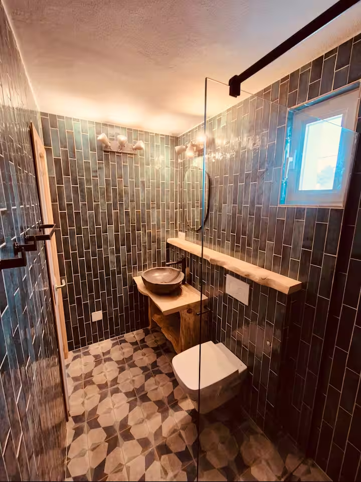 Walk-in shower room with green tiles and patterned floor